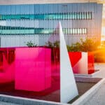 A view of Centennial campus at dawn or dusk, with the sunlight reflecting on the Reds and Whites art installation outside the Hunt Library.