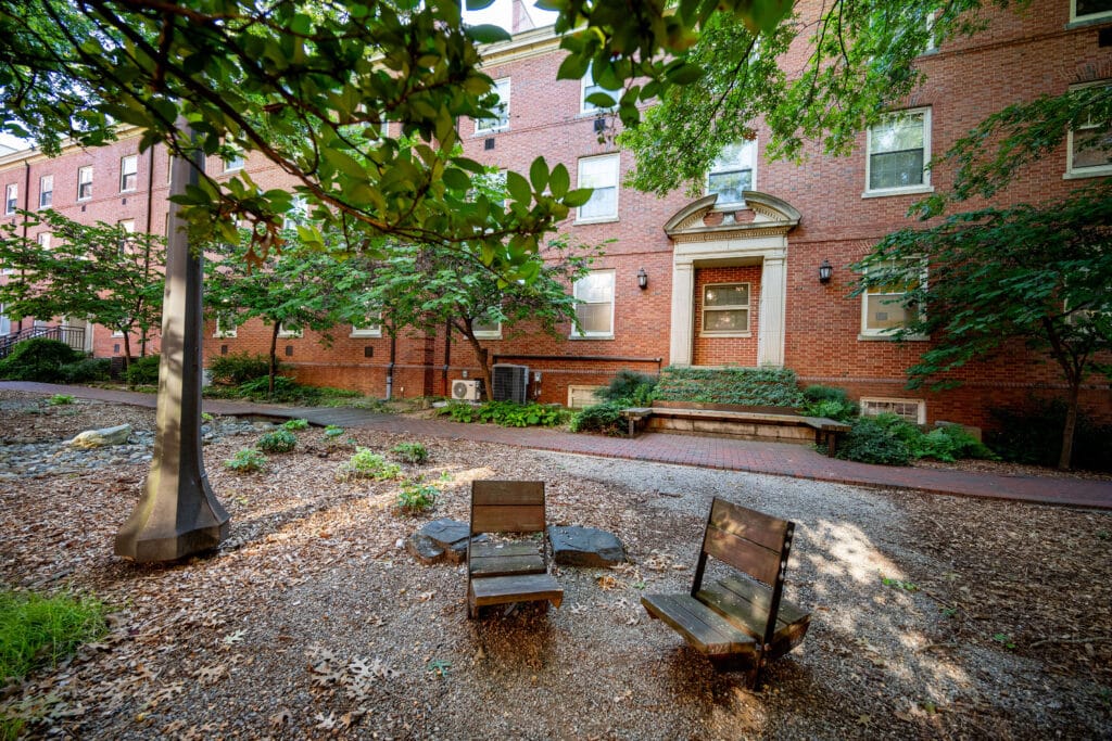 Two wooden chairs and a small flower garden in the Artists' Backyard