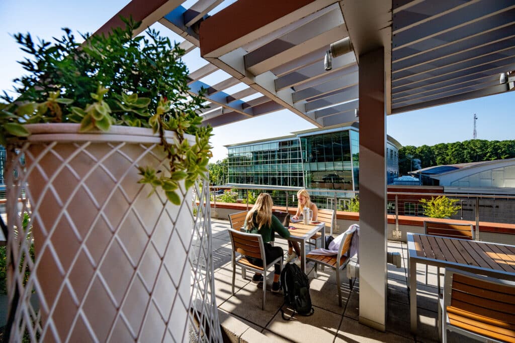 Two students sit at a table on the patio of Talley Student Union, overlooking the Wellness and Recreation Center.