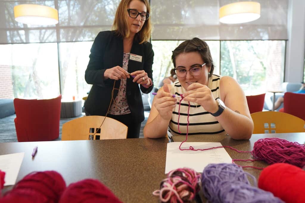 Two people at a table with yarns of different colors.