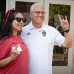 Chancellor Woodson poses with an NC State student while showing the Wolf Ears hand signal.