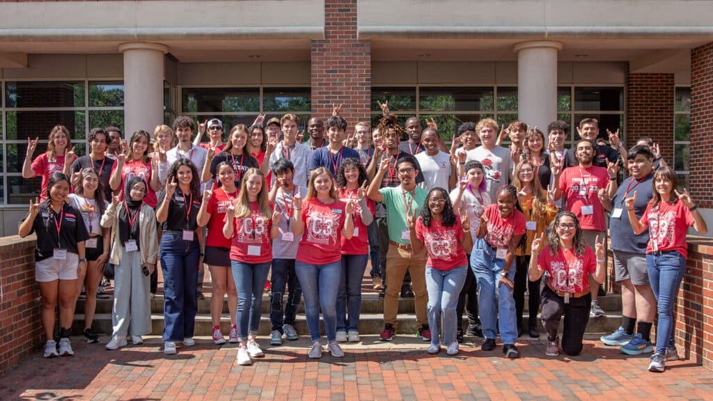 A group photo of C3 program students holding up wolfie hand gestures.