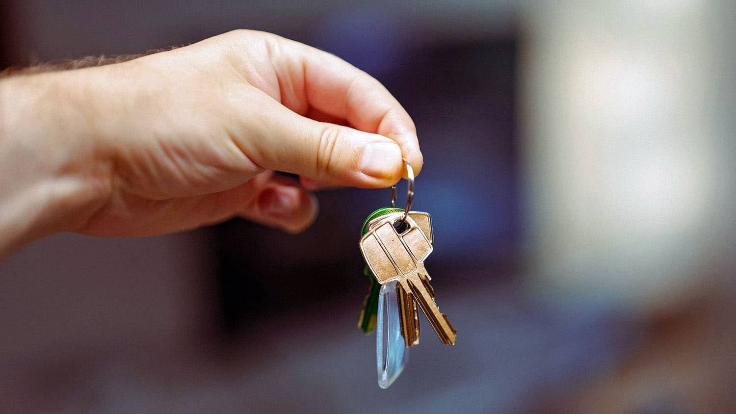 a man's hand is holding out a set of house keys