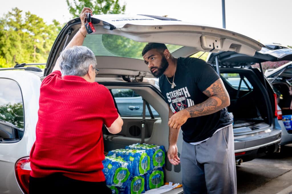 Vann and a volunteer place water bottles in the back of a van