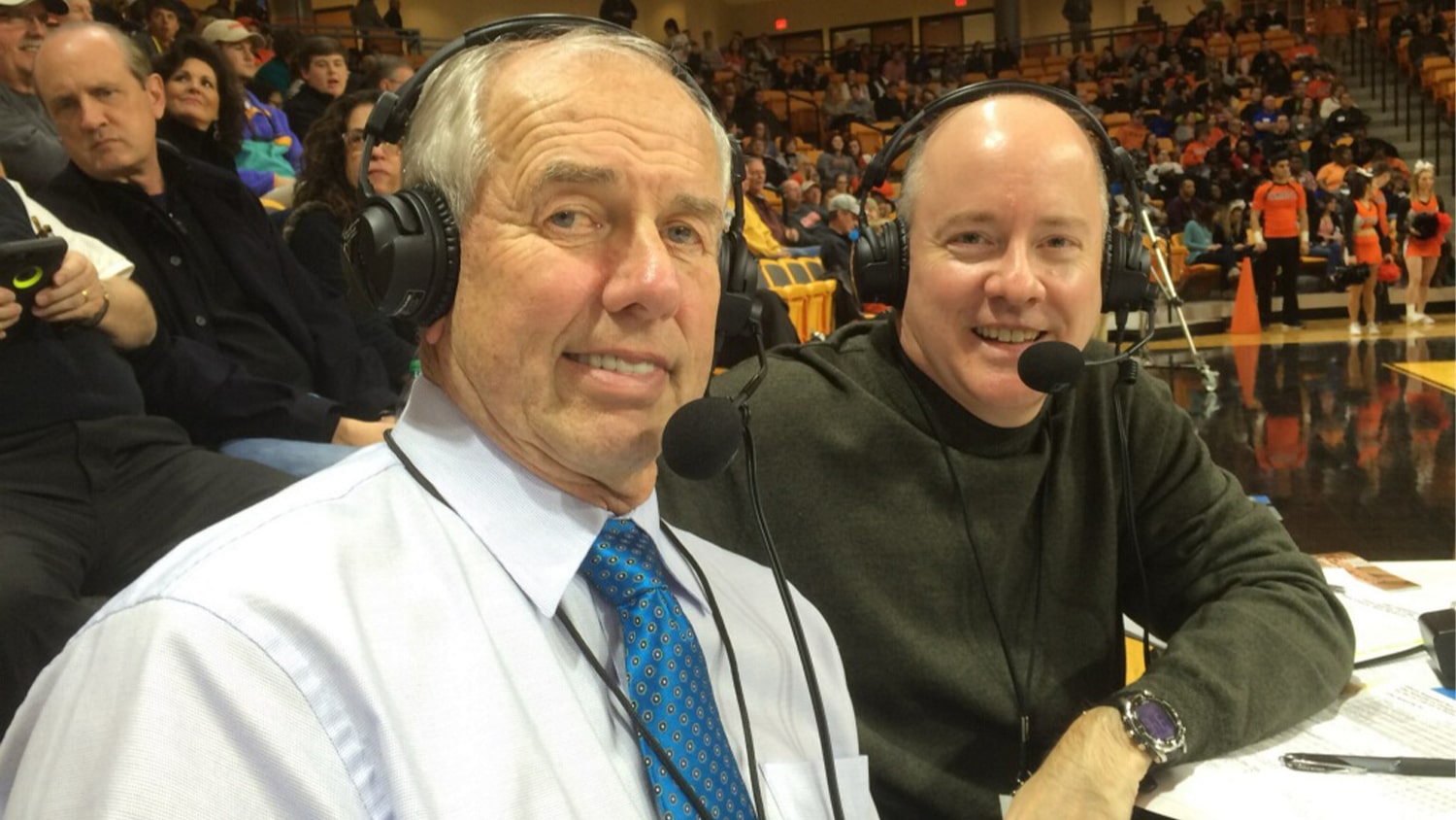 Brian Hall and another broadcaster with their headsets on at a basketball game