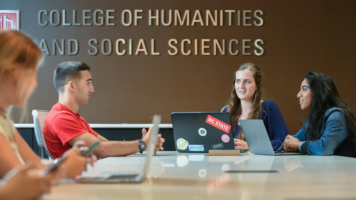 Students sit around a table and work together