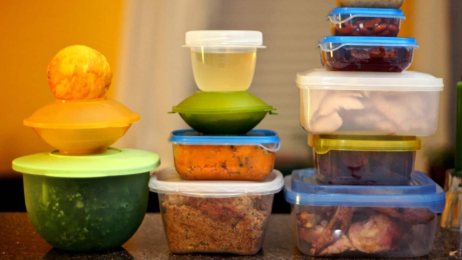 three stacks of food storage containers containing leftover food. storing leftovers properly reduces the risk of foodborne illness.