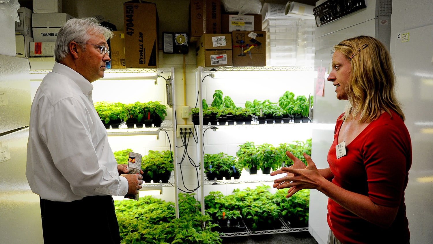 Randy Woodson discusses horticultural research in front of a row of plants inside the Mountain Horticultural Crops Research and Extension Center.