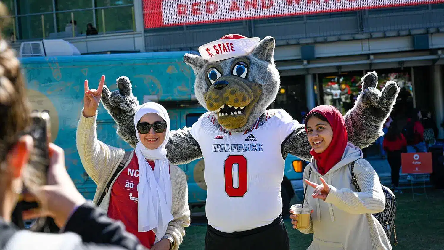 Two students pose with Mr. Wuf