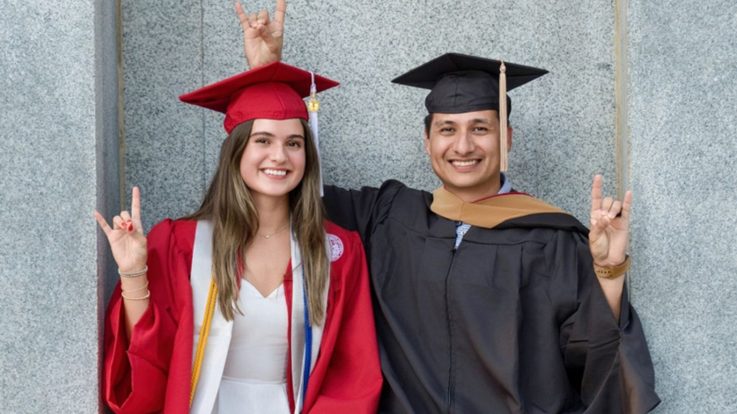 David Beltran and his daughter, Alexia, wearing their graduation caps and gowns at the Memorial Belltower