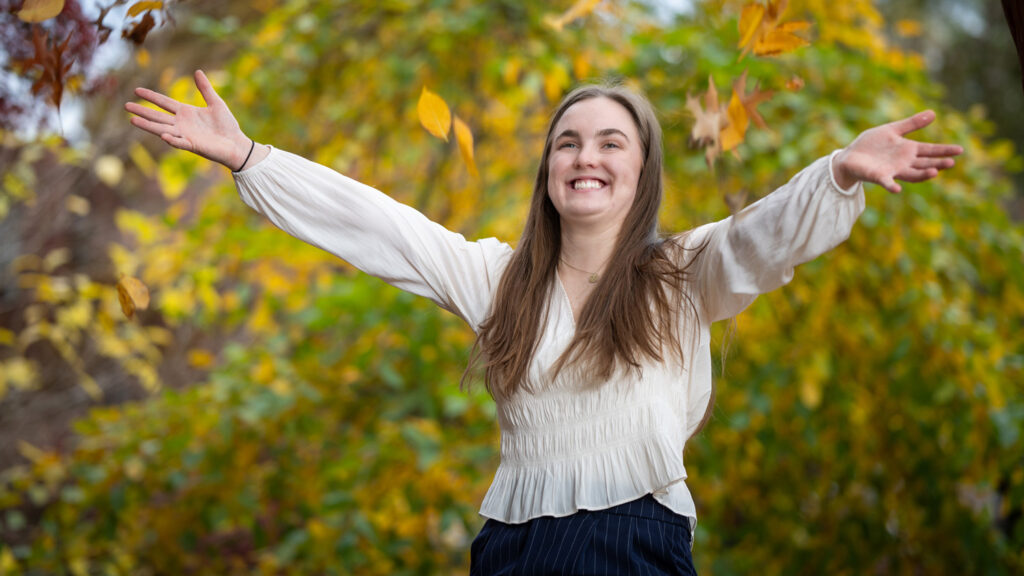 Lauren Turner throws up leaves on NC State's campus on a fall day