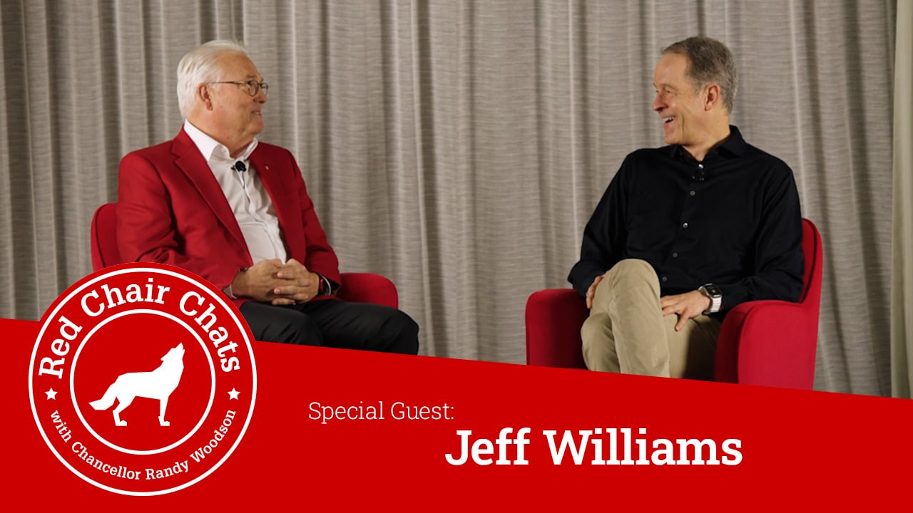 Chancellor Woodson and Jeff Williams sit on stage in red chairs. A graphic with the Red Chair Chats logo says "Red Chair Chats with Chancellor Woodson, Special Guest Jeff Williams"