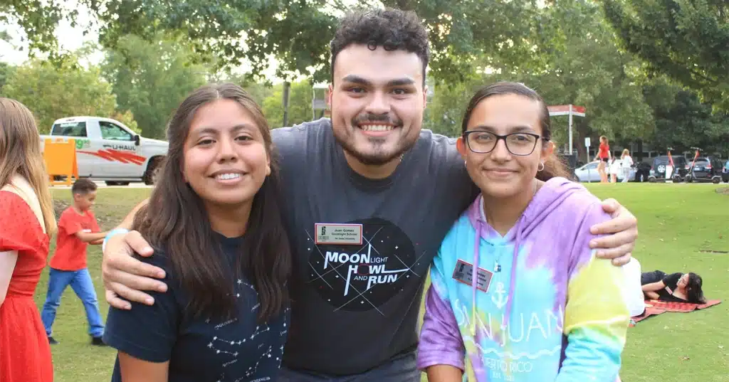 Three students pose smiling outside at a food truck rodeo.