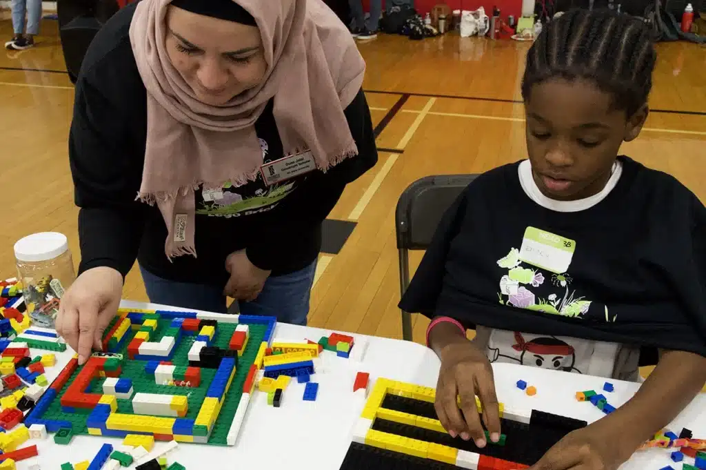 A Goodnight Scholar helps a child build with Legos for an activity.