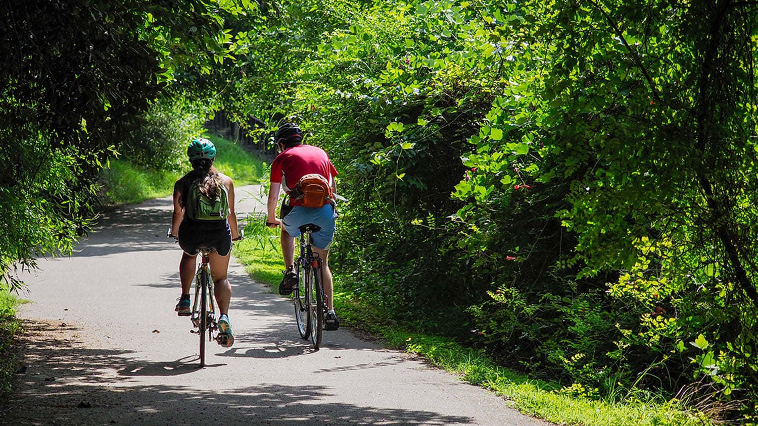 Two people on bicycles on a paved path.