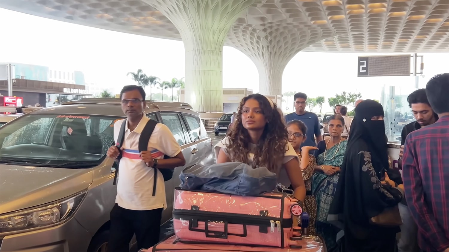 A student pushes suitcases through a crowd at the Mumbai airport.