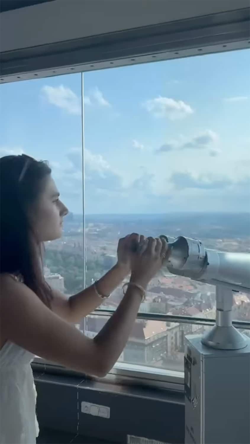 A student looks through a telescope in an elevated viewing platform in Prague. 