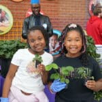 Two children show off their new strawberry plants in front of the horticultural science exhibit. 