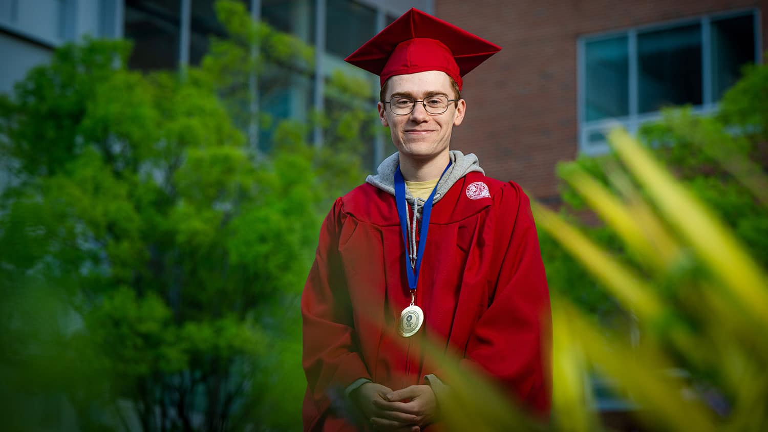 Josh Ott, a spring 2025 NC State graduate, poses in cap and gown in the leadup to commencement.