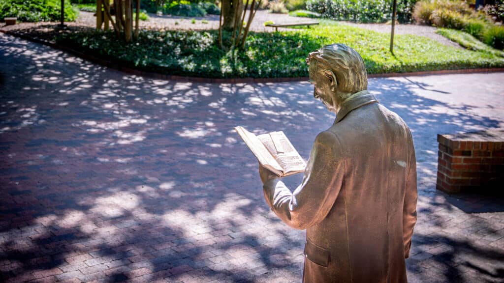 The strolling professor statue, a well-known campus landmark in NC State’s Gardner Arboretum.