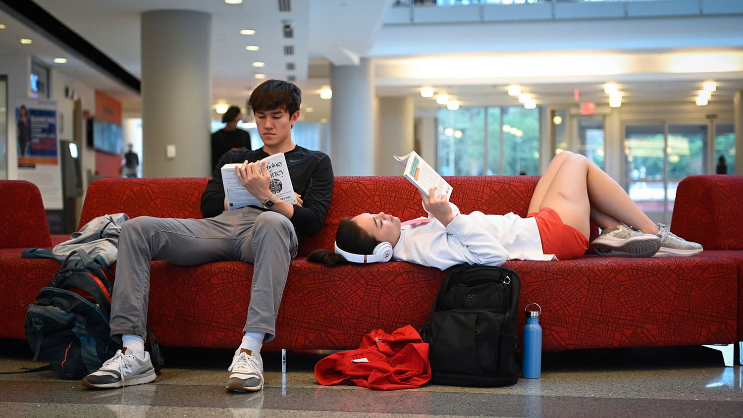 Two NC State students relax and read on a couch in Talley Student Union.