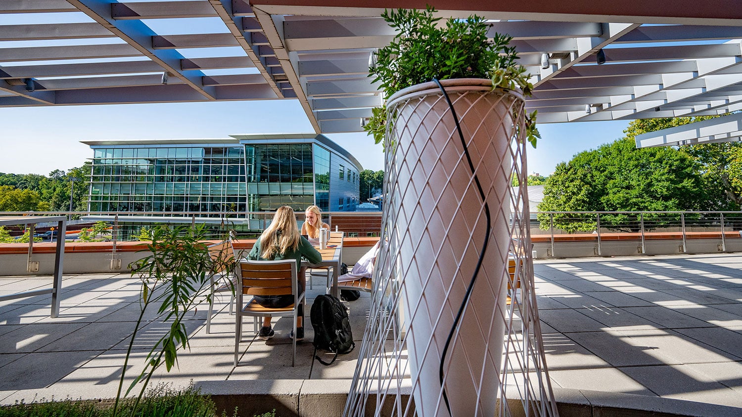 Two students sit at a shaded table on a terrace outside Talley Student Union