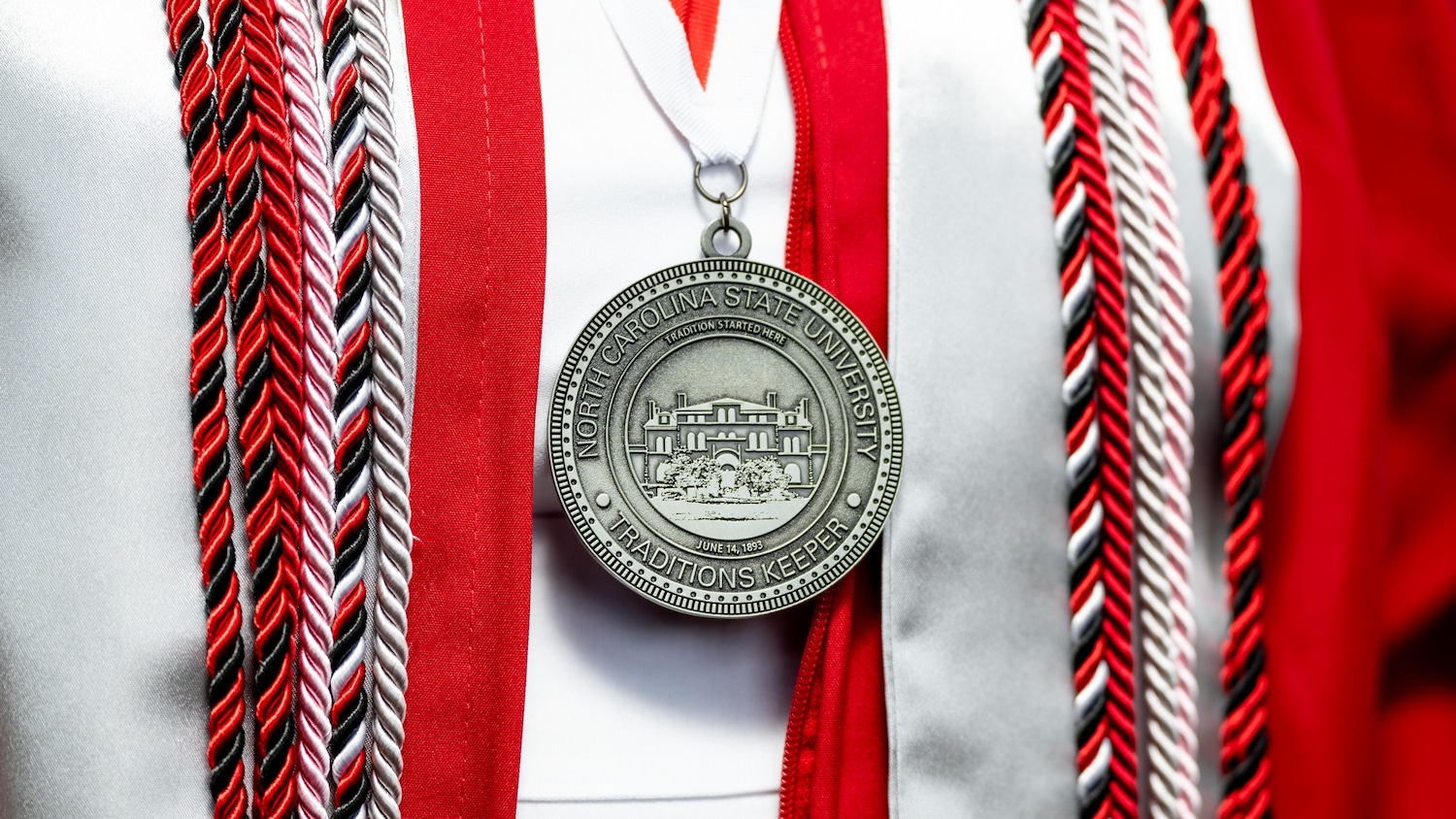 A Traditions Keeper medal is worn by a Chancellor's Aide at the Memorial Belltower for cap and gown photos.