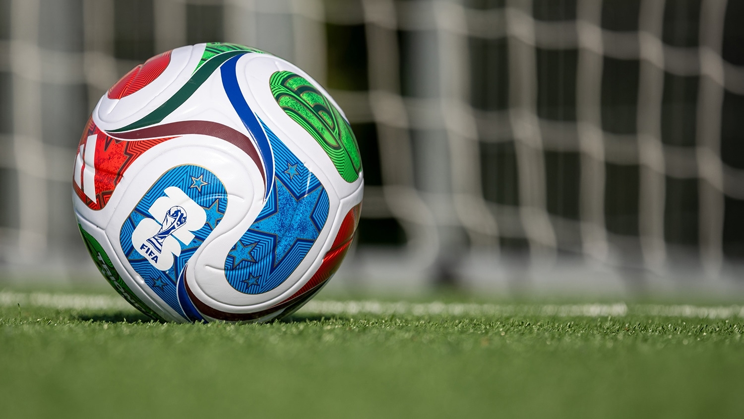 view of World Cup soccer ball resting on turf with view of goal net in the background