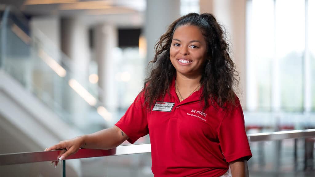 a student inside of Tally Student Union wears a red t-shirt and smiles for a photo