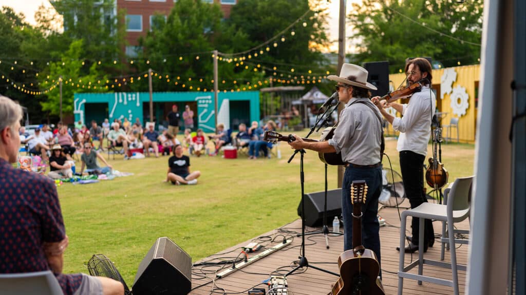 A band performs for a crowd on the grassy lawn at The Corner.